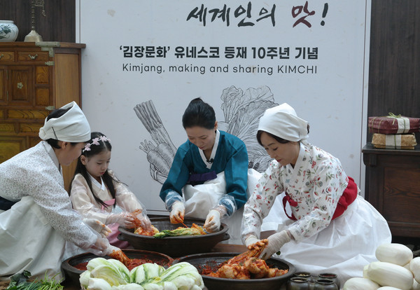 22일 서울 양재동 aT센터에서 열린 '제4회 김치의 날' 행사에서 전통적인 방식으로 한 집안의 3대가 모여 김치를 담그고 이웃과 나누는 김장문화를 재연하고 있다.