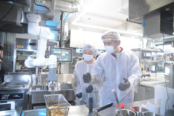 오유경 식품의약품안전처장(왼쪽)이 24일 서울 소재의 로봇이 조리하는 음식점을 방문해 치킨, 파스타 조리 현장을 둘러보고 있다.